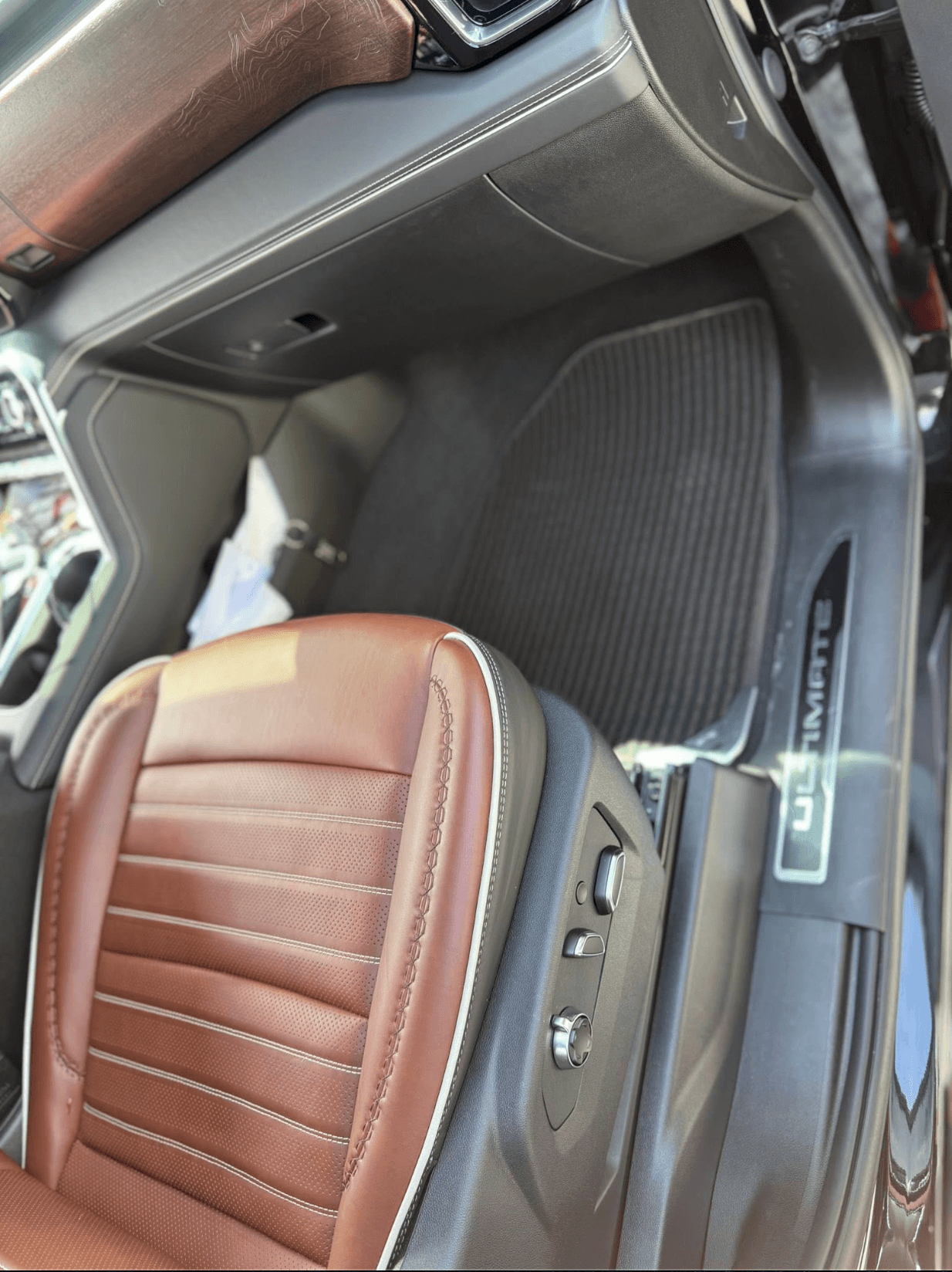 Close-up of cognac leather seat and Ultimate-branded floor mat in a GMC Sierra after a deep clean